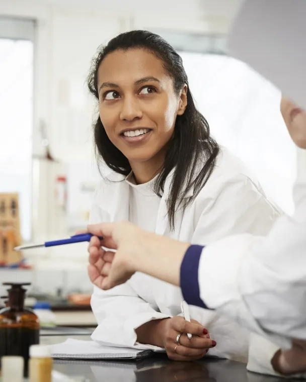 An african american female scientist smiles at a colleague